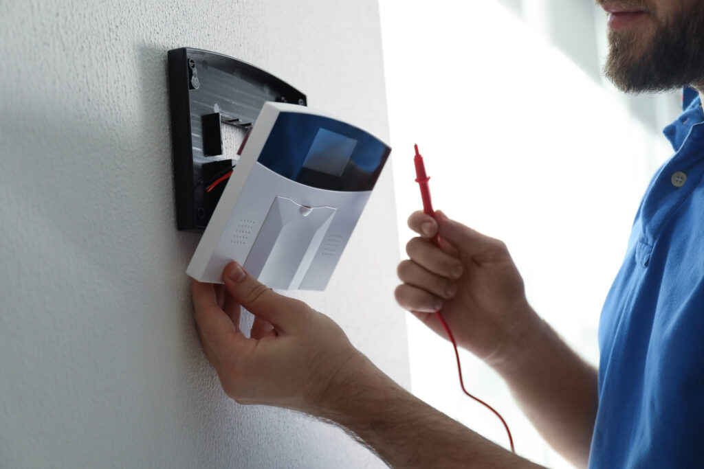 man,installing,home,security,system,on,white,wall,in,room,